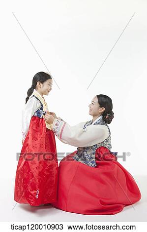 Stock Image - mother fixing daughter's Hanbok. Fotosearch