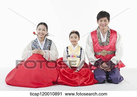 Stock Image - parents and a daughter in Hanbok sitting on a floor. Fotosearch