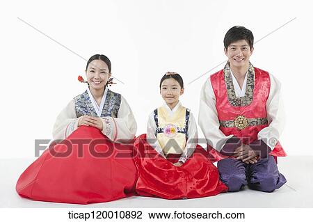 Stock Image - parents and a daughter in Hanbok sitting on a floor. Fotosearch