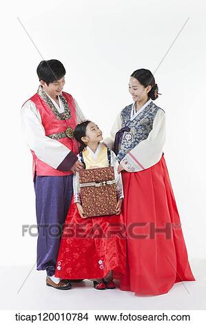 Picture - parents in Hanbok standing behind a daughter holding a present . Fotosearch