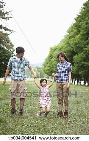 Stock Image - parents swinging a daughter . Fotosearch