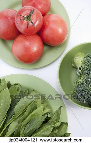 Stock Image - tomatoes, broccoli and spinach in each green plate. Fotosearch