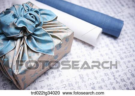 Stock Image - traditional papers next to a package wrapped in a traditional wrap with nice big ribbon . Fotosearch