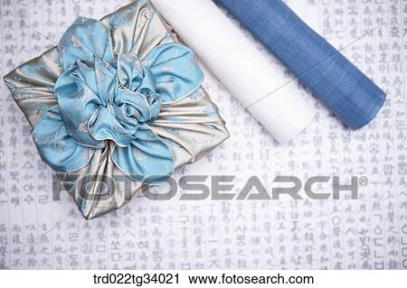 Stock Image - traditional papers next to a package wrapped in a traditional wrap with nice big ribbon . Fotosearch