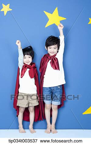 Stock Photo - two boys wearing red capes raising up their arms like a superman. Fotosearch
