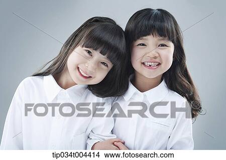 Picture - two female kids smiling together with arm in arm . Fotosearch