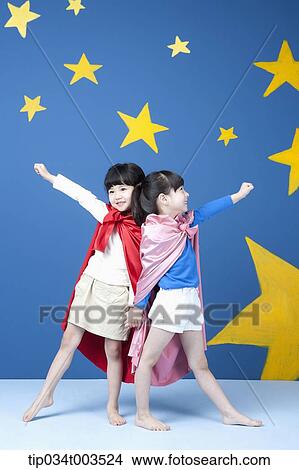Picture - two girls wearing superman capes posing like superman. Fotosearch