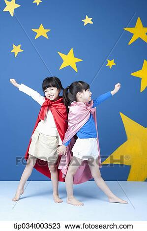 Stock Image - two girls wearing superman capes posing like superman. Fotosearch
