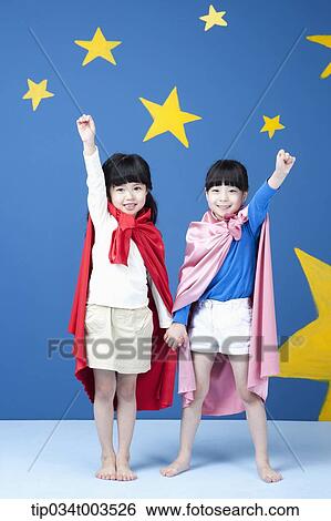 Stock Photograph - two girls with superman capes spreading their arm like a superman. Fotosearch