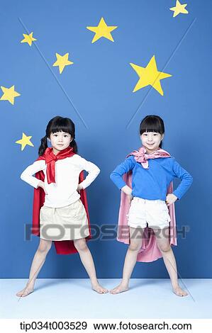 Stock Photo - two girls with superman capes standing like a superman. Fotosearch