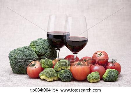 Picture - two glasses of red wine with broccoli and tomatoes. Fotosearch