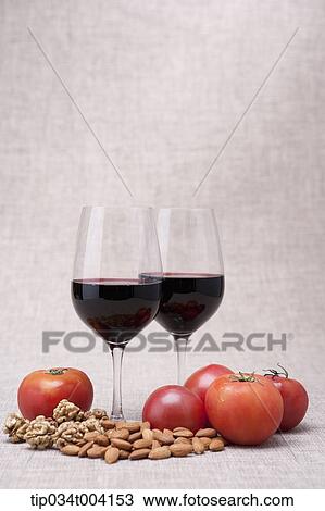 Stock Image - two glasses of red wine with nuts and tomatoes. Fotosearch