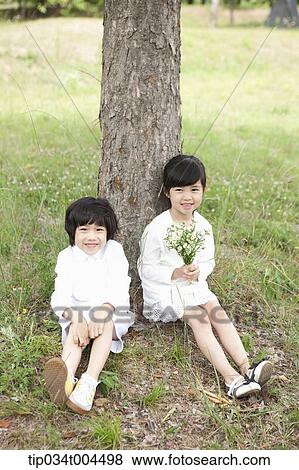 Stock Photo - two kids sitting under a tree. Fotosearch