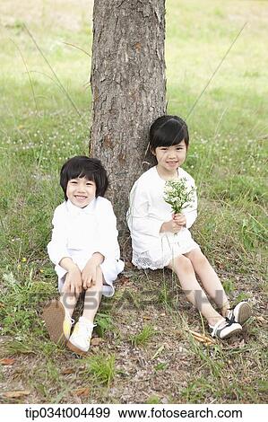 Stock Photo - two kids sitting under a tree. Fotosearch