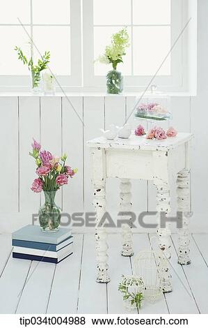 Stock Photo - vase with flowers on a pile of books, table and near window. Fotosearch