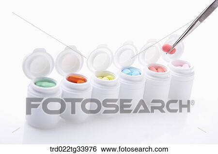 Stock Photograph - white drug bottles filled up with different colours of medicine tablets . Fotosearch