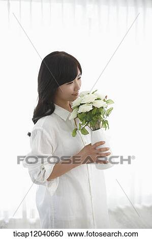 woman wearing white shirt and holding a flower vase View Large Photo Image Stock Image - woman wearing white shirt and holding a flower vase . Fotosearch