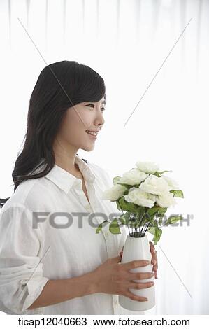 woman wearing white shirt and holding a flower vase View Large Photo Image Stock Image - woman wearing white shirt and holding a flower vase . Fotosearch