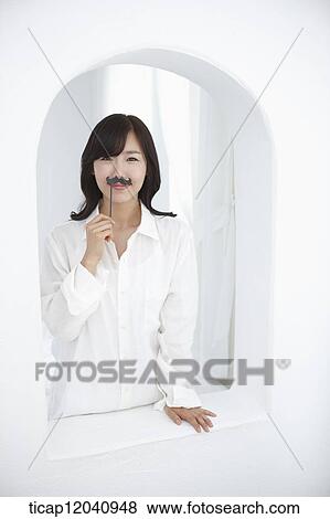 woman wearing white shirt and holding a mustache figure View Large Photo Image Stock Photo - woman wearing white shirt and holding a mustache figure. Fotosearch
