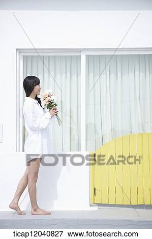 woman wearing white shirt and walking next to the house with a bouquet View Large Photo Image Stock Photo - woman wearing white shirt and walking next to the house with a bouquet. Fotosearch