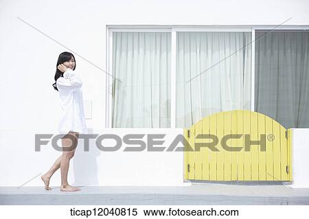 woman wearing white shirt and walking next to the house View Large Photo Image Stock Photography - woman wearing white shirt and walking next to the house. Fotosearch