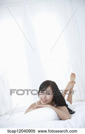 Stock Photography - woman wearing white sleepwear and lying on the pillow. Fotosearch