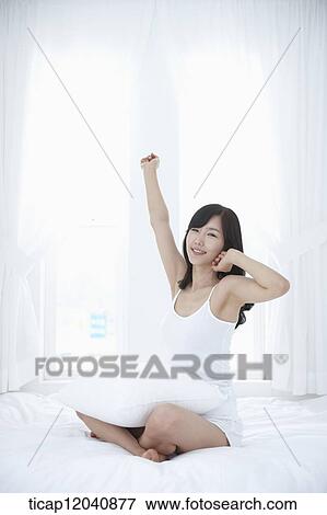 Stock Photo - woman wearing white sleepwear and stretching out her body . Fotosearch