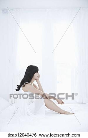 woman wearing white sleepwear and sitting on the bed View Large Photo Image Stock Photograph - woman wearing white sleepwear and sitting on the bed . Fotosearch