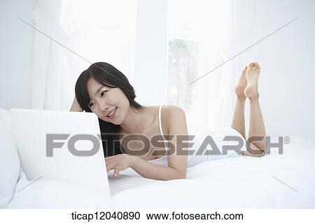 woman wearing white sleepwear and using the laptop on the bed View Large Photo Image Stock Image - woman wearing white sleepwear and using the laptop on the bed . Fotosearch