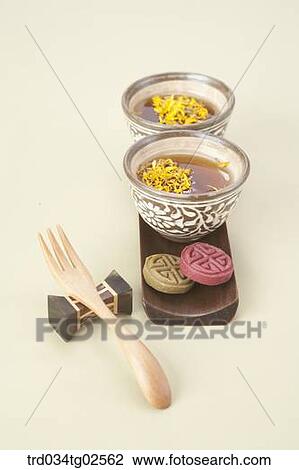 Stock Image - yellow chrysanthemums flower tea in mug cups with Korean finger cake and a fork. Fotosearch
