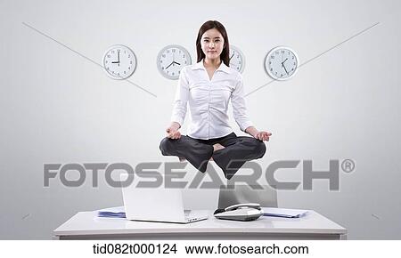 Stock Illustration - a business woman meditating on top of her desk. Fotosearch