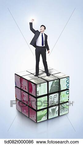 Stock Illustration - a businessman on Rubik's cube with currencies. Fotosearch