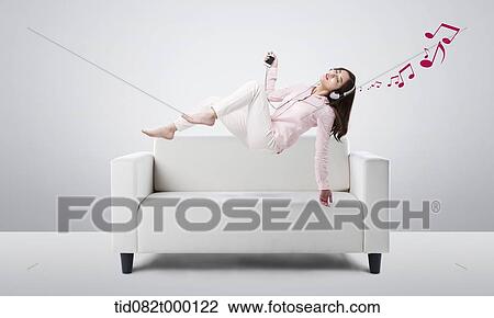 a woman listening to music on a sofa View Large Illustration Drawing - a woman listening to music on a sofa. Fotosearch