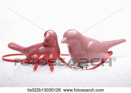 Stock Illustration - red porcelain birds, red ribbon and wedding rings. Fotosearch