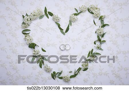 Stock Illustration - wedding rings inside flowers in a heart shape. Fotosearch