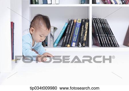 Stock Image - a baby crawling under a desk . Fotosearch