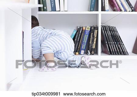 Stock Image - a baby crawling under a desk . Fotosearch