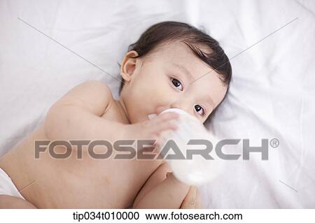 Stock Image - a baby drinking milk on the bed. Fotosearch