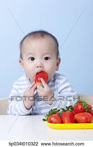 Stock Image - a baby having a strawberry. Fotosearch