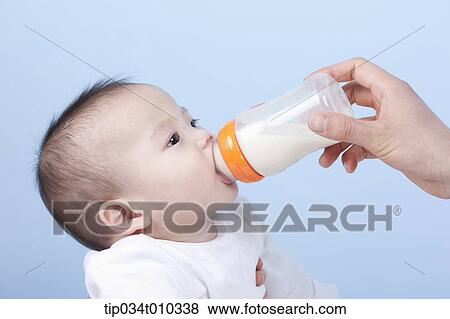 Stock Photo - a baby having milk with a bottle. Fotosearch