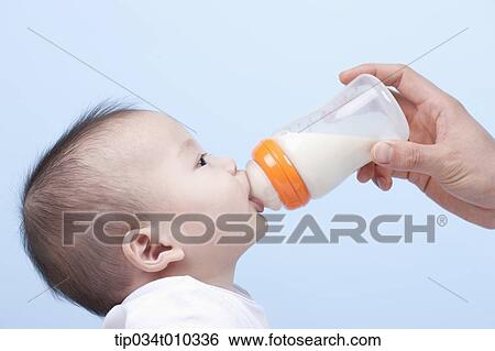 Stock Photograph - a baby having milk with a bottle. Fotosearch