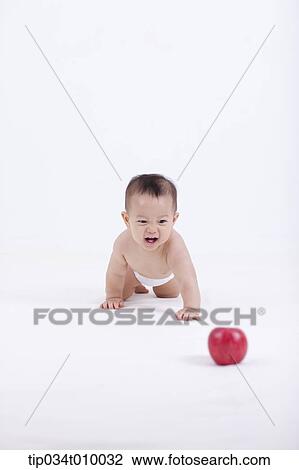 Stock Image - a baby in diaper crawling to an apple. Fotosearch