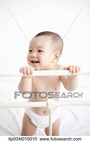 Stock Image - a baby in diaper playing in the crib. Fotosearch