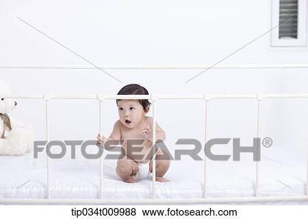 Stock Photo - a baby in diaper playing in the crib. Fotosearch