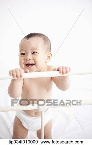 Stock Photo - a baby in diaper playing in the crib. Fotosearch