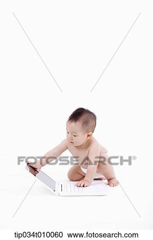 Stock Image - a baby in diaper playing with a laptop. Fotosearch