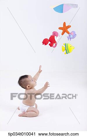 Stock Image - a baby in diaper with mobiles hanging in the ceiling. Fotosearch