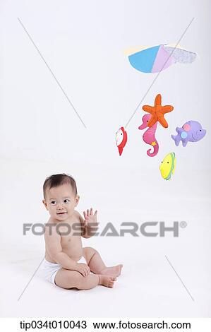 Stock Image - a baby in diaper with mobiles hanging in the ceiling. Fotosearch