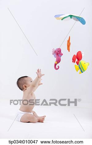 A Baby In Diaper With Mobiles Hanging In The Ceiling Stock