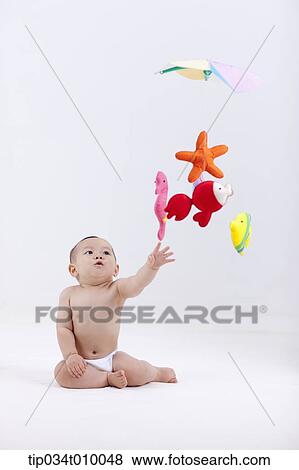 A Baby In Diaper With Mobiles Hanging In The Ceiling Stock Photo
